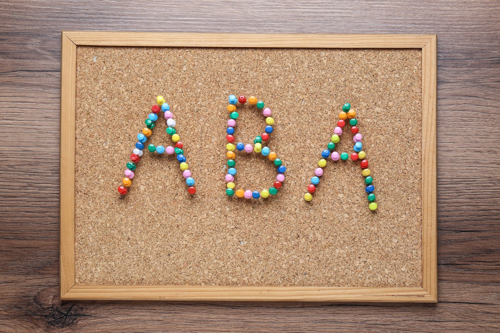 Applied Behavior Analysis Concept. Corkboard with Abbreviation ABA Made of Colorful Pins on Wooden Table, Top View